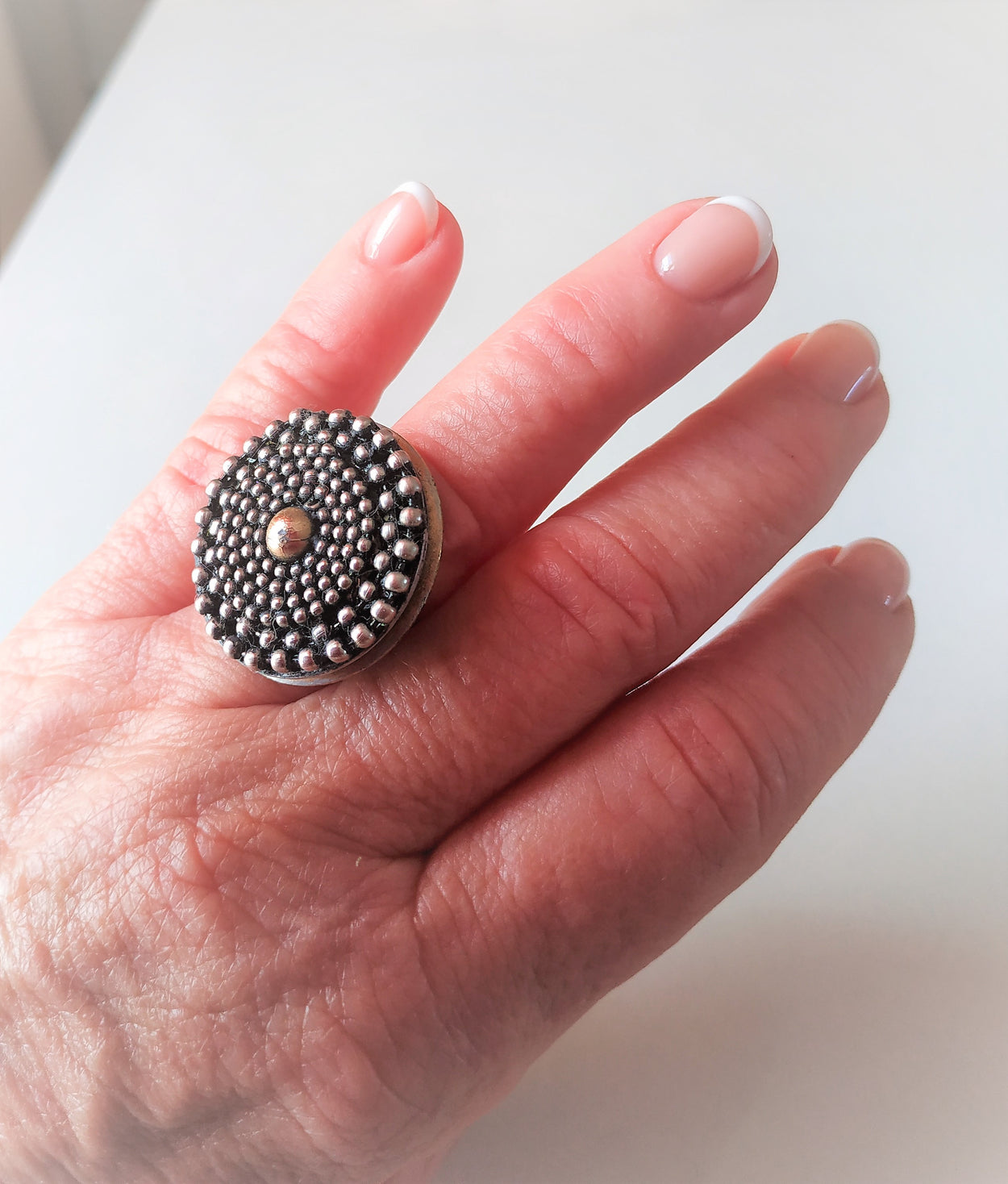 Unique white metal ring with a yellow metal ball in the center