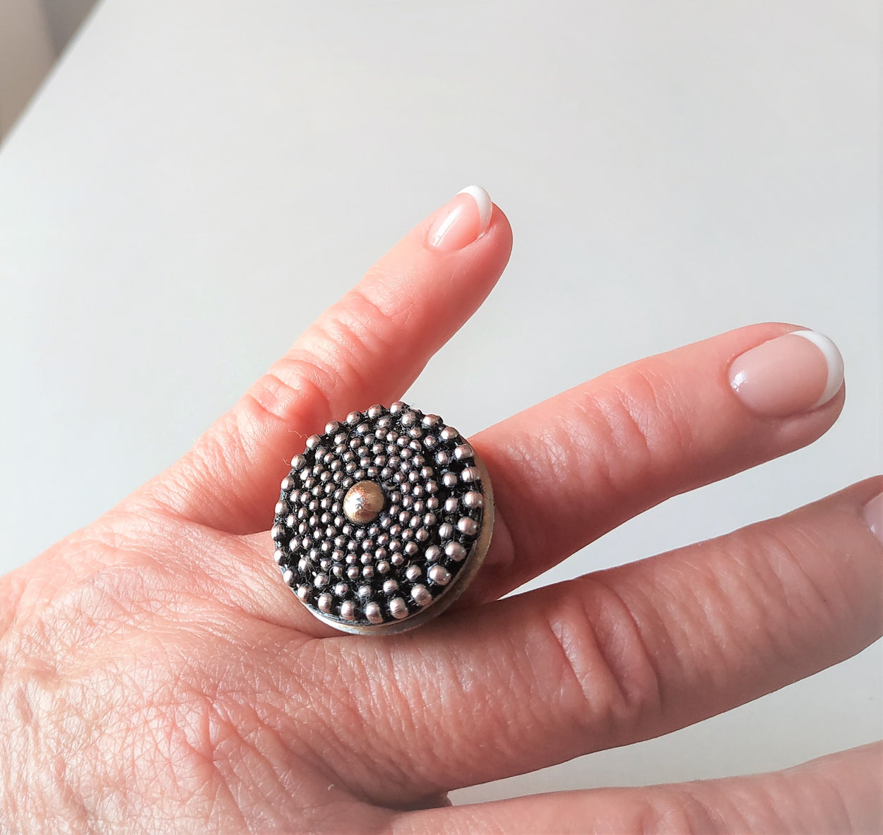 Unique white metal ring with a yellow metal ball in the center