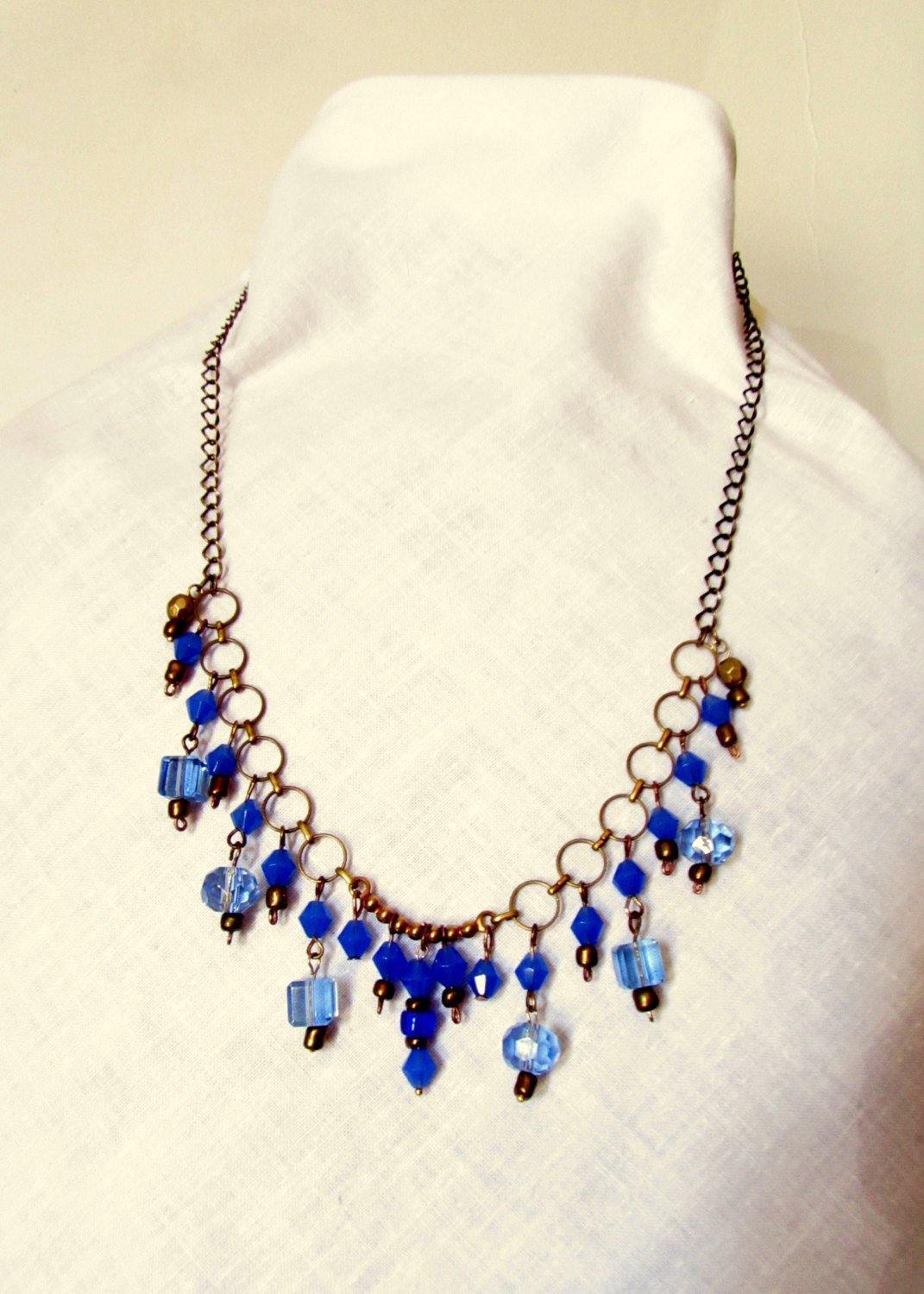 Necklace made of light and dark blue glass beads and gold small beads on a chain of yellow metal - GLEZANT designer goods store.
