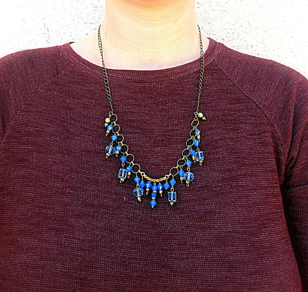 Necklace made of light and dark blue glass beads and gold small beads on a chain of yellow metal - GLEZANT designer goods store.