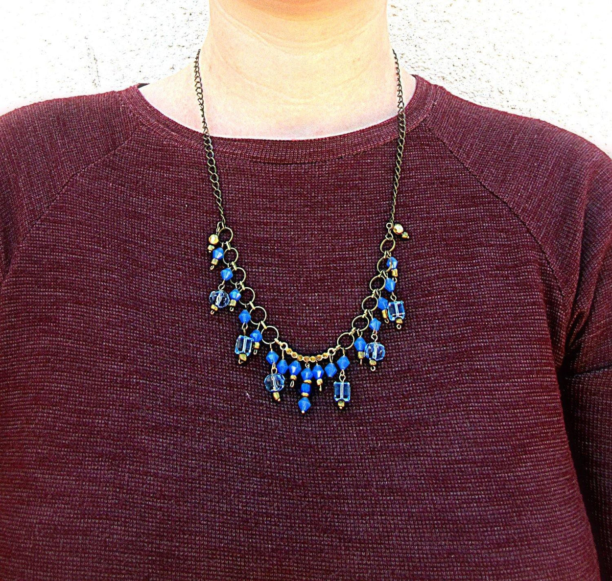 Necklace made of light and dark blue glass beads and gold small  beads on a chain of yellow metal - GLEZANT designer goods store. 